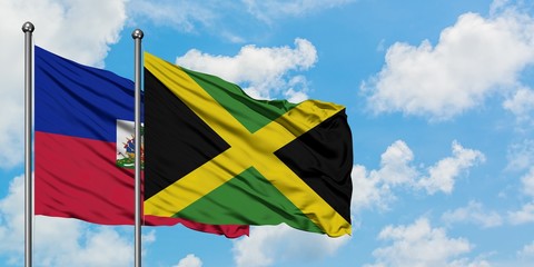Haiti and Jamaica flag waving in the wind against white cloudy blue sky together. Diplomacy concept, international relations.