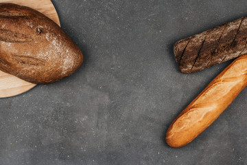  Loafs of rye and wheat bread on a dark gray background with space for text. Fresh crisp bread.