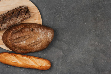  Loafs of rye and wheat bread on a dark gray background with space for text. Fresh crisp bread.