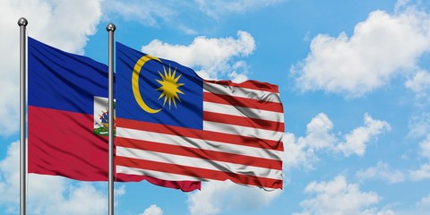 Haiti and Malaysia flag waving in the wind against white cloudy blue sky together. Diplomacy concept, international relations.