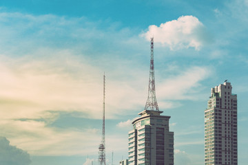 retro broadcasting pole or radio signal tower on the top of the building in the city with the evening sky. vintage tone photo and film style.