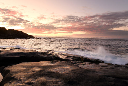 Dawn on the shore of the Atlantic Ocean. Waves crash against the rocky shore and the island in the background Atlantic Ocean. USA. Maine.  Nubble york 