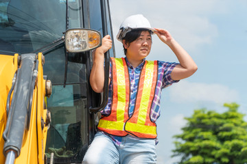 The Asian female engineer are standing on the backhoe And stood looking towards the construction site The concept of equal ability between men and women © Prot