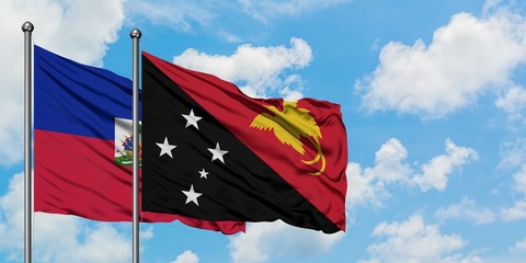 Haiti and Papua New Guinea flag waving in the wind against white cloudy blue sky together. Diplomacy concept, international relations.