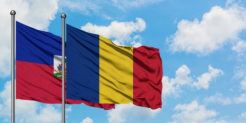 Haiti and Romania flag waving in the wind against white cloudy blue sky together. Diplomacy concept, international relations.