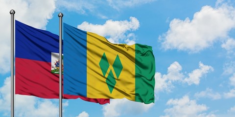 Haiti and Saint Vincent And The Grenadines flag waving in the wind against white cloudy blue sky together. Diplomacy concept, international relations.