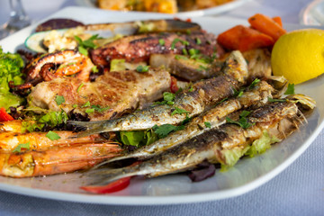 Big plate with seafood, sepia, fish, shrimps, mussels served with retsina, in taverna in Greece