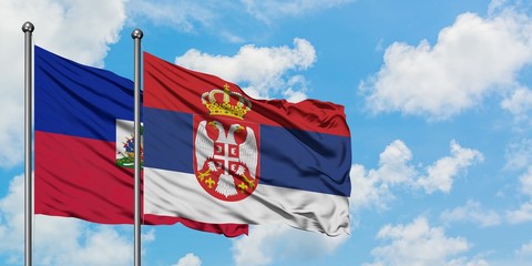 Haiti and Serbia flag waving in the wind against white cloudy blue sky together. Diplomacy concept, international relations.