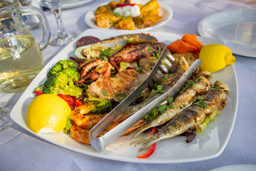 Big plate with seafood, sepia, fish, shrimps, mussels served with retsina, in taverna in Greece