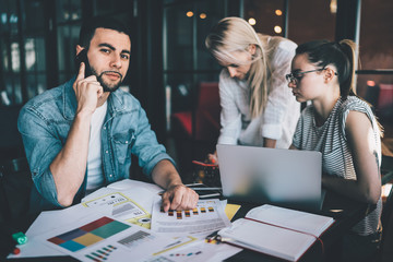 Man speaking on phone sitting with coworkers