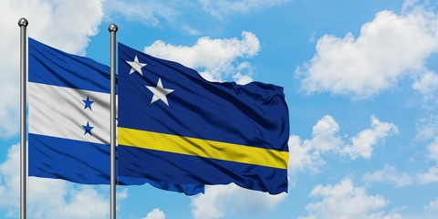 Honduras and Curacao flag waving in the wind against white cloudy blue sky together. Diplomacy concept, international relations.