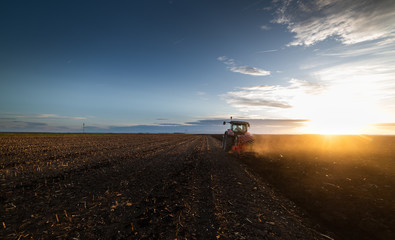 Tractor plowing fields in sunset