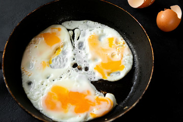 ried eggs in a pan, eggshell on a black background closeup - Powered by Adobe