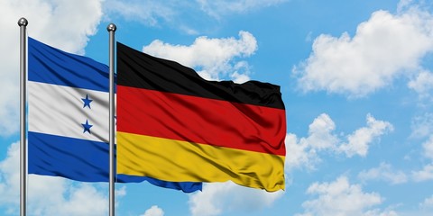 Honduras and Germany flag waving in the wind against white cloudy blue sky together. Diplomacy concept, international relations.