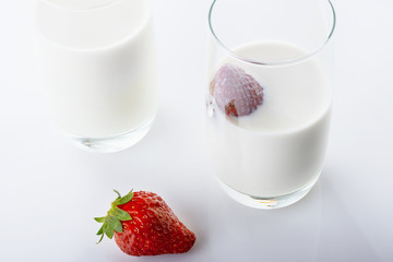Fresh, juicy strawberry in cream on white background. Close up. Selective focus. High key.