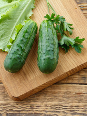 Just picked cucumbers and leaves of salad lying on cutting board.