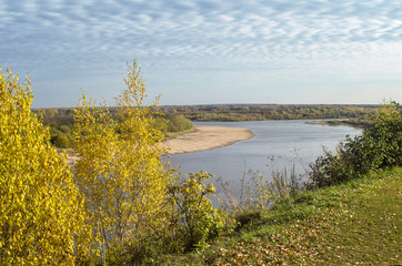 Autumn view of the water surface of the river with overgrown picturesque banks and Cirrus clouds in the blue sky, a clear horizon, copy space.