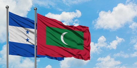 Honduras and Maldives flag waving in the wind against white cloudy blue sky together. Diplomacy concept, international relations.