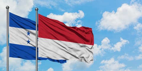 Honduras and Monaco flag waving in the wind against white cloudy blue sky together. Diplomacy concept, international relations.