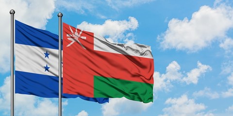 Honduras and Oman flag waving in the wind against white cloudy blue sky together. Diplomacy concept, international relations.