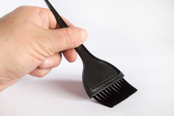Black brush for coloring hair in hand on a white background.