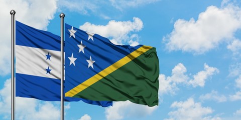 Honduras and Solomon Islands flag waving in the wind against white cloudy blue sky together. Diplomacy concept, international relations.
