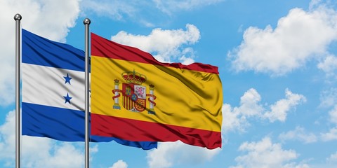 Honduras and Spain flag waving in the wind against white cloudy blue sky together. Diplomacy concept, international relations.