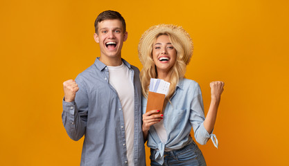 Happy couple holding passports with tickets celebrating getting a visa