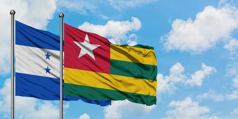 Honduras and Togo flag waving in the wind against white cloudy blue sky together. Diplomacy concept, international relations.