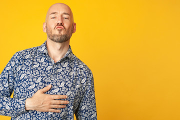 Fabulous at any age. Portrait of 40-year-old man sending air kiss over light yellow background in...