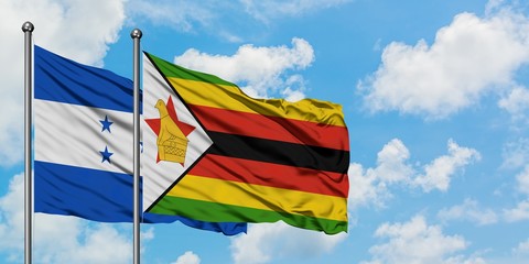 Honduras and Zimbabwe flag waving in the wind against white cloudy blue sky together. Diplomacy concept, international relations.