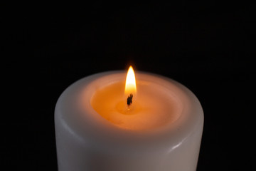 burning white candle large on a black background