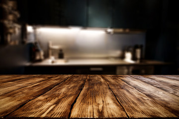 Wooden table background of free space for your decoration and blurred background of kitchen. Copy space.Dark mood interior. Kitchen furniture. 