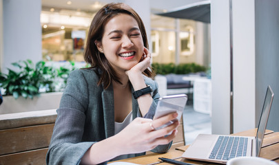 Cheerful young Asian woman using smartphone