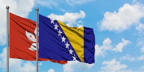 Hong Kong and Bosnia Herzegovina flag waving in the wind against white cloudy blue sky together. Diplomacy concept, international relations.