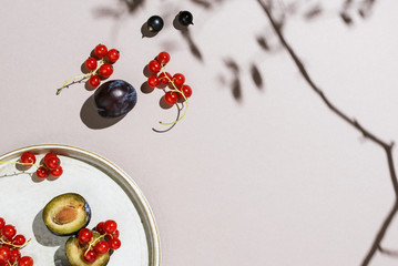Minimalist flatlay of plums and berries on a handmade plate, selective focus