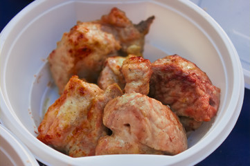 Serving of barbecue in a white disposable plate close-up.