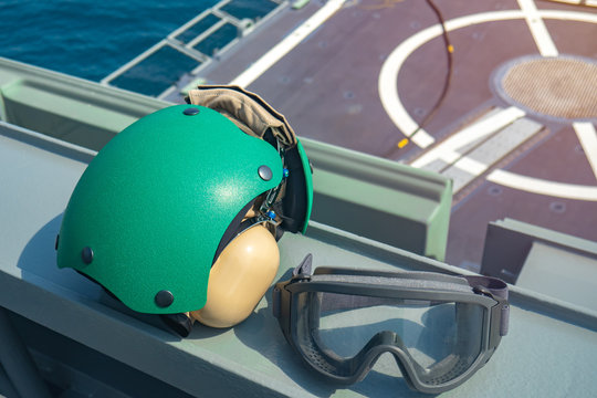 Military flight helicopter helmet with protection glasses with aviation deck on the ocean background.