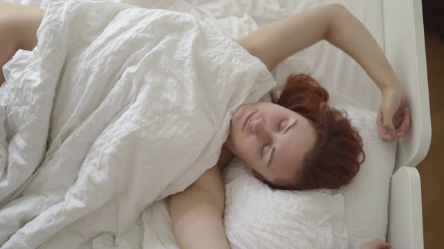 Redhead woman's lazy morning in a sunny vintage room with no clothes and naked body parts - Laying in bed under blanket