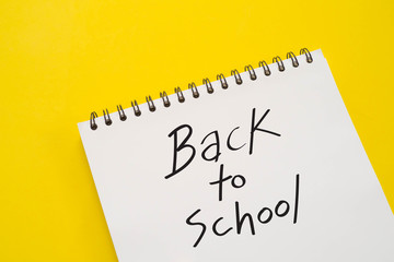 Back to school word in notebook on yellow background