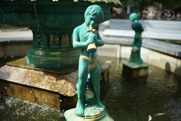 Fountain with boys who pours water from the vessel. Cupid statue.