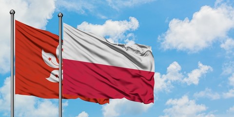 Hong Kong and Poland flag waving in the wind against white cloudy blue sky together. Diplomacy concept, international relations.