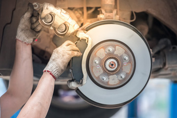 Close-up view of the car disc brakes, car disc brakes on the back, disc discs worn during the malfunction of the brake system, with the disc turned on for maintenance.