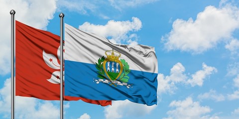 Hong Kong and San Marino flag waving in the wind against white cloudy blue sky together. Diplomacy concept, international relations.
