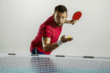 Answer. Young man plays table tennis on white studio background. Model plays ping pong. Concept of leisure activity, sport, human emotions in gameplay, healthy lifestyle, motion, action, movement. - obrazy, fototapety, plakaty