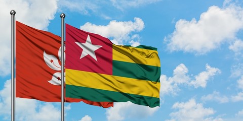 Hong Kong and Togo flag waving in the wind against white cloudy blue sky together. Diplomacy concept, international relations.