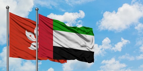Hong Kong and United Arab Emirates flag waving in the wind against white cloudy blue sky together. Diplomacy concept, international relations.