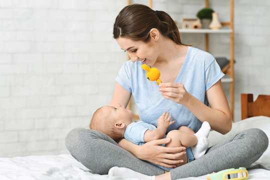 Mother playing with her infant child using developing toy