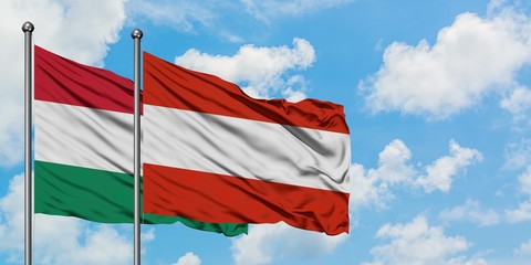 Hungary and Austria flag waving in the wind against white cloudy blue sky together. Diplomacy concept, international relations.