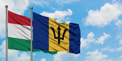 Hungary and Barbados flag waving in the wind against white cloudy blue sky together. Diplomacy concept, international relations.